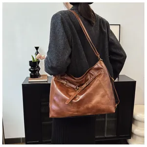 Bolso tote vintage marrón en piel sintética con hebillas usado por una modelo mujer