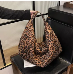 Detail showing the large capacity tote bag with classic leopard print on a leather chair