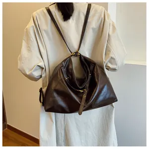 Detalle de bolso tote de cuero marrón oscuro con ojales metálicos y correas ajustables