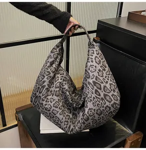 Detail of grey leopard print tote bag on a black leather chair with wide handle and zipper
