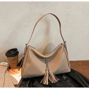 Close-up of beige tote bag with fringe detail on black leather and autumn accessories