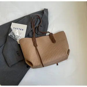 Top view of a woven tote bag with brown straps styled with a blazer and glass for commute