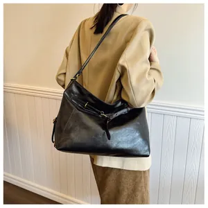 Detalle de bolso hobo de cuero negro brillante con detalles de hebillas metálicas doradas
