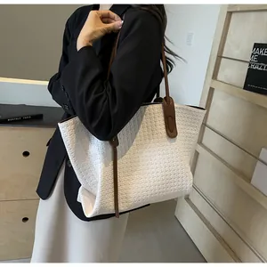 Detailed close-up of woven white tote bag texture with brown leather strap detail
