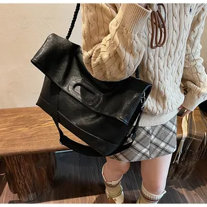 Détail d'un grand sac cabas en cuir noir avec design à rabat élégant et bandoulière large