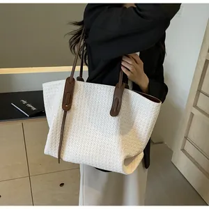 Detailed view of white woven tote bag with brown leather straps held by a model