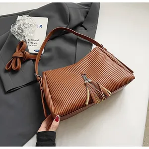 Detailed view of brown pleated tote bag with tassels on grey blazer suit background