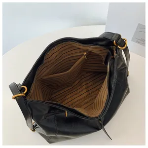 Vista superior de bolso hobo negro con forro de rayas marrones y bolsillos internos
