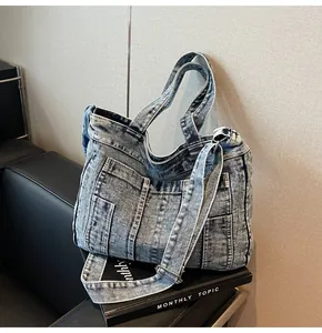 Detail of vintage washed blue denim tote bag on books with adjustable shoulder strap