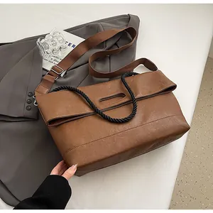 Détail d'un grand cabas en similicuir marron avec sangle tisée sur blazer gris