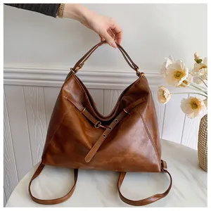 Detalle de un bolso tote de cuero marrón vintage con textura fina y hebillas metálicas