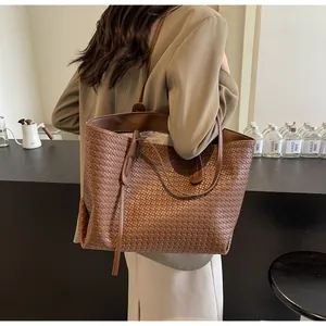 Close-up of woven texture on brown leather tote bag with long shoulder strap