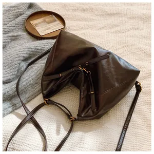 Detalle de bolso tote de cuero marrón oscuro con correa ajustable y hebilla dorada vintage