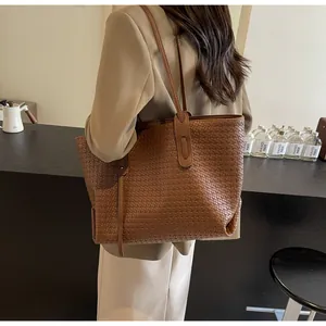 Detailed close-up of brown woven texture on large tote bag with reinforced handle