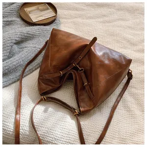 Detalle de bolso tote de cuero marrón suave con textura vintage y herrajes de bronce