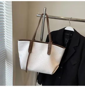 Detail of woven texture on cream tote bag with brown leather handles on a hanger