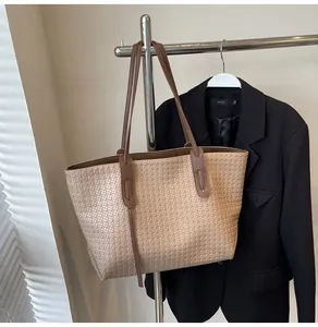 Macro detail of the woven texture and premium leather handle on a large apricot tote bag