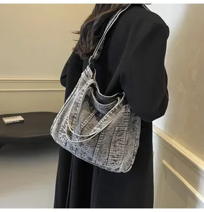 Detail of dark gray washed denim tote bag with decorative vertical stitching on shoulder