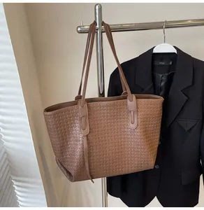 Detail of brown woven texture and slim shoulder straps on a large tote bag for commuting