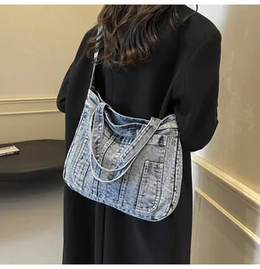 Detail view of washed denim tote bag showing multi-pocket design and wide shoulder straps