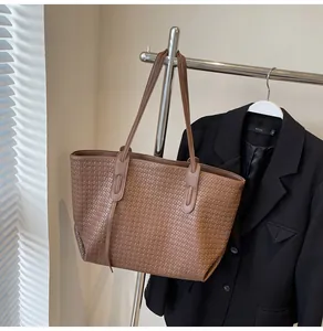 Close-up of brown woven tote bag texture with slim straps hanging on metal hanger