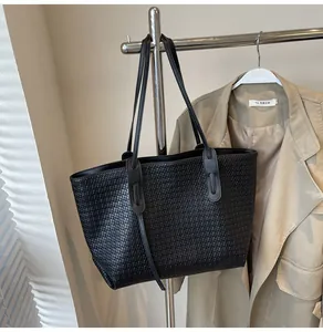 Detail of classic woven texture on black tote bag with slim shoulder straps for office