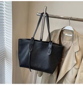 Close-up of the black woven texture and minimalist shoulder strap on large tote bag