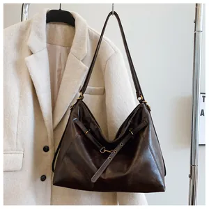 Detalle de bolso tote de piel encerada marrón oscuro con hebilla en un perchero