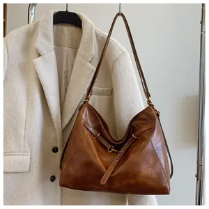 Detalle del bolso tote grande de cuero marrón caramelo con anillas metálicas vintage