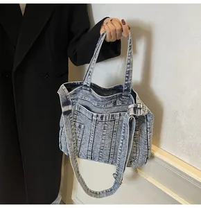 Detail view of washed denim tote with vertical stitching and adjustable metal buckle strap