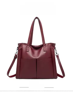 Détail d'un sac cabas bordeaux en cuir grainé avec poignées et bandoulière amovible