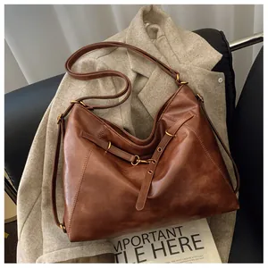 Primer plano de bolso tote de cuero vintage marrón sobre traje gris con hebillas