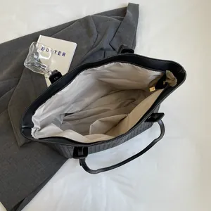 Minimalist black woven tote bag featuring a spacious interior and top zipper closure