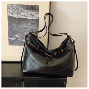 Detalle de un bolso tote grande negro vintage de cuero brillante con herrajes dorados