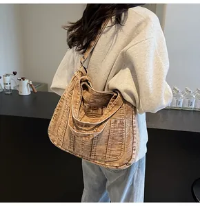 Detail of vintage washed denim tote bag with functional multi-pockets in caramel brown