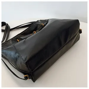 Vista detallada superior de bolso tote negro de cuero sintético con aros metálicos dorados