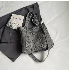 Detailed view of gray washed denim tote bag with functional pockets and long shoulder strap