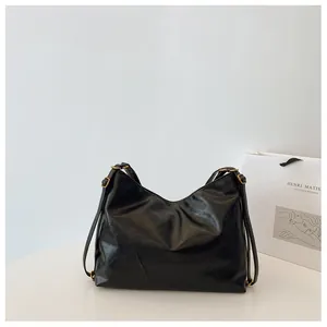 Detalle del bolso tote de cuero negro brillante con hebilla ajustable dorada