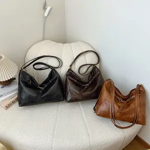 Bolsos tote vintage grandes de cuero negro y marrón en un sofá acogedor
