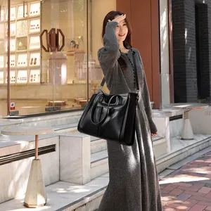 Sac fourre-tout noir minimaliste avec texture litchi et bandoulière sur mannequin