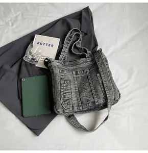 Detail of washed grey denim tote bag with metal buckle strap and vintage texture