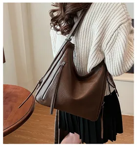 Detail view of large brown PU leather tote bag with stylish tassel zipper on model