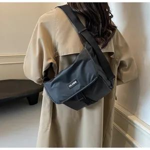 Rear view of a model wearing the waterproof black crossbody bag with a casual trench coat