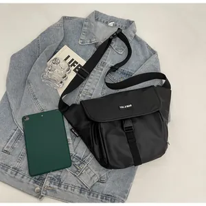 Close-up of black waterproof crossbody bag with buckle closure on denim jacket