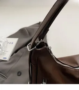 Detail of silver polished D-ring hardware and zipper on dark brown leather tote bag