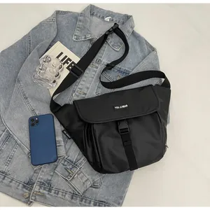Detail of waterproof crossbody bag with clip buckle and logo tag on denim background