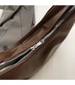 Detailed close-up of smooth silver metal zipper on vintage brown leather tote bag