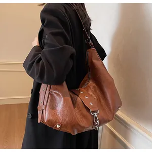 Detail of a brown tote bag with silver star studs and vintage leather texture on model