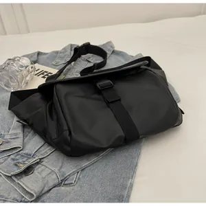Detail of waterproof black messenger bag with buckle closure on denim jacket background