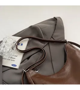Detail view of smooth brown leather shoulder bag with neat stitching and silver zipper